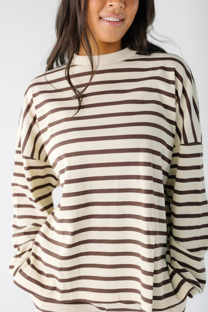 Close view of a woman wearing a cream and brown stripe lounge set with long, loose sleeves.