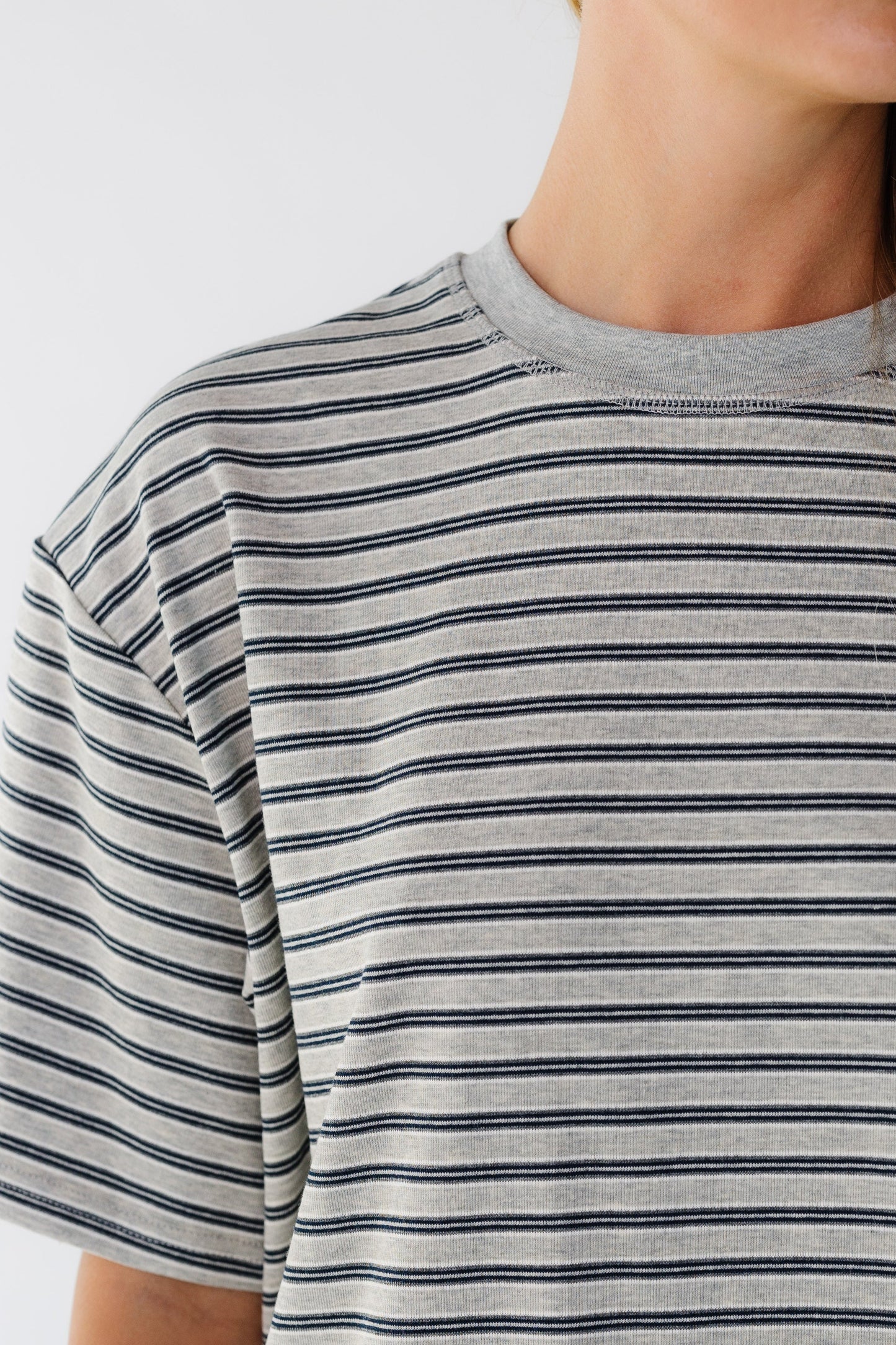 Close view of a grey stripe loose fitting tee with short sleeves.