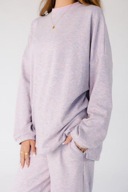 Close view of a woman wearing a pink and lavender narrow stripe lounge set with side pant pockets.