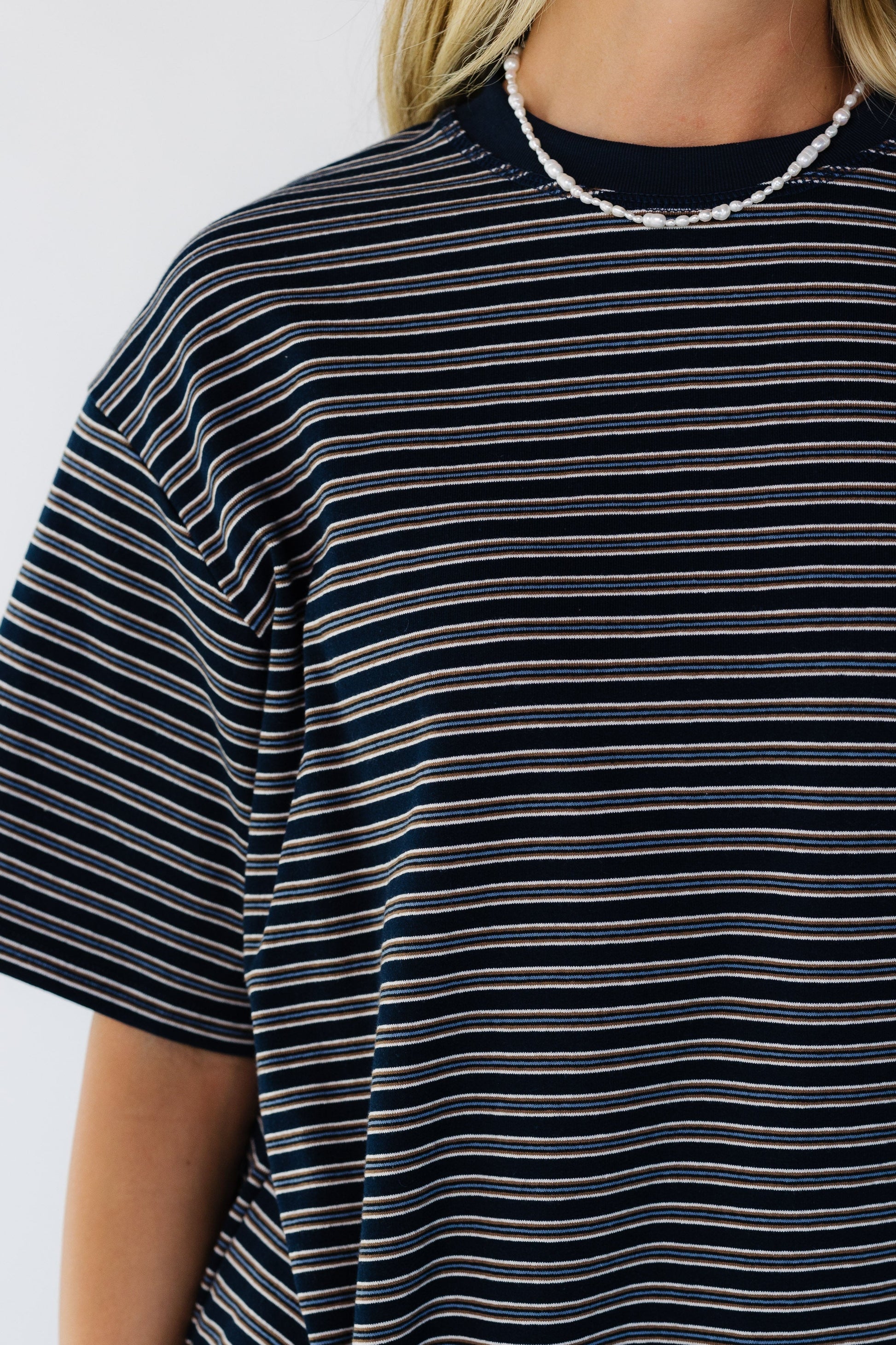 Close viewof a woman wearing a navy short sleeve stripe tee.