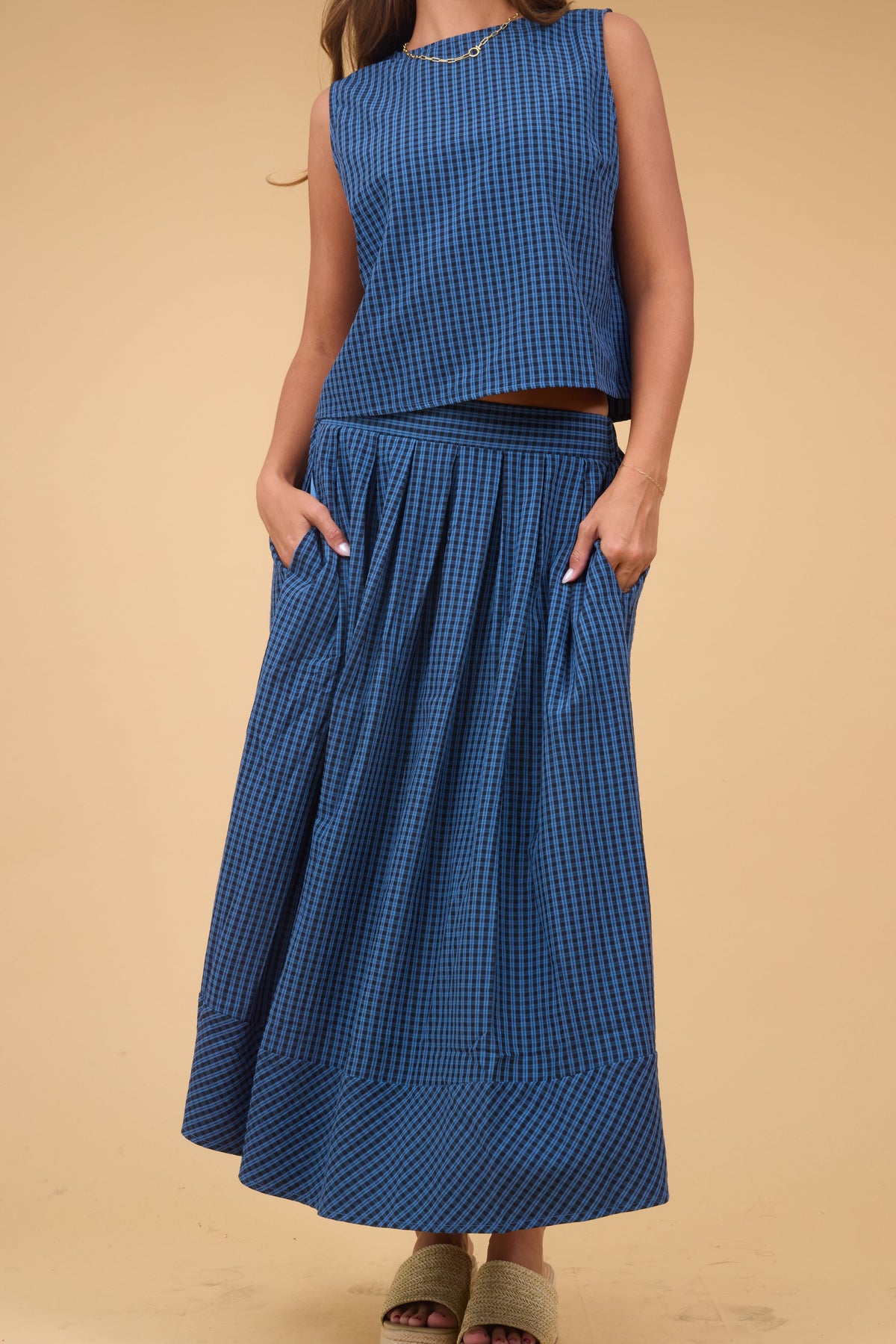 A woman wearing a loose fitting navy & black plaid midi skirt and matching swing top.
