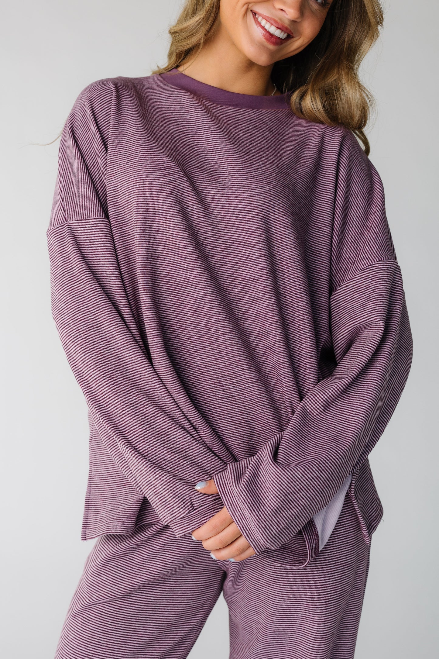 Close view of a woman wearing a loose fitting lounge set in berry purple with long sleeves.  