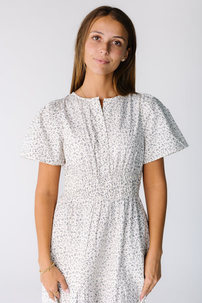 Close view of a woman wearing  white print dress with a slash-V-neckline and short sleeves in a white floral print
