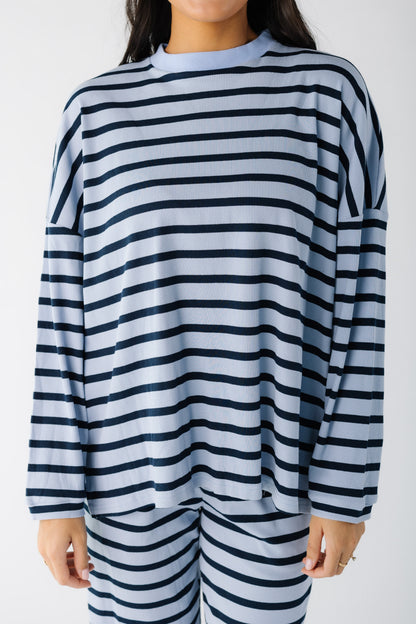 Close view of a young woman wearing a light blue and navy stripe lounge top.