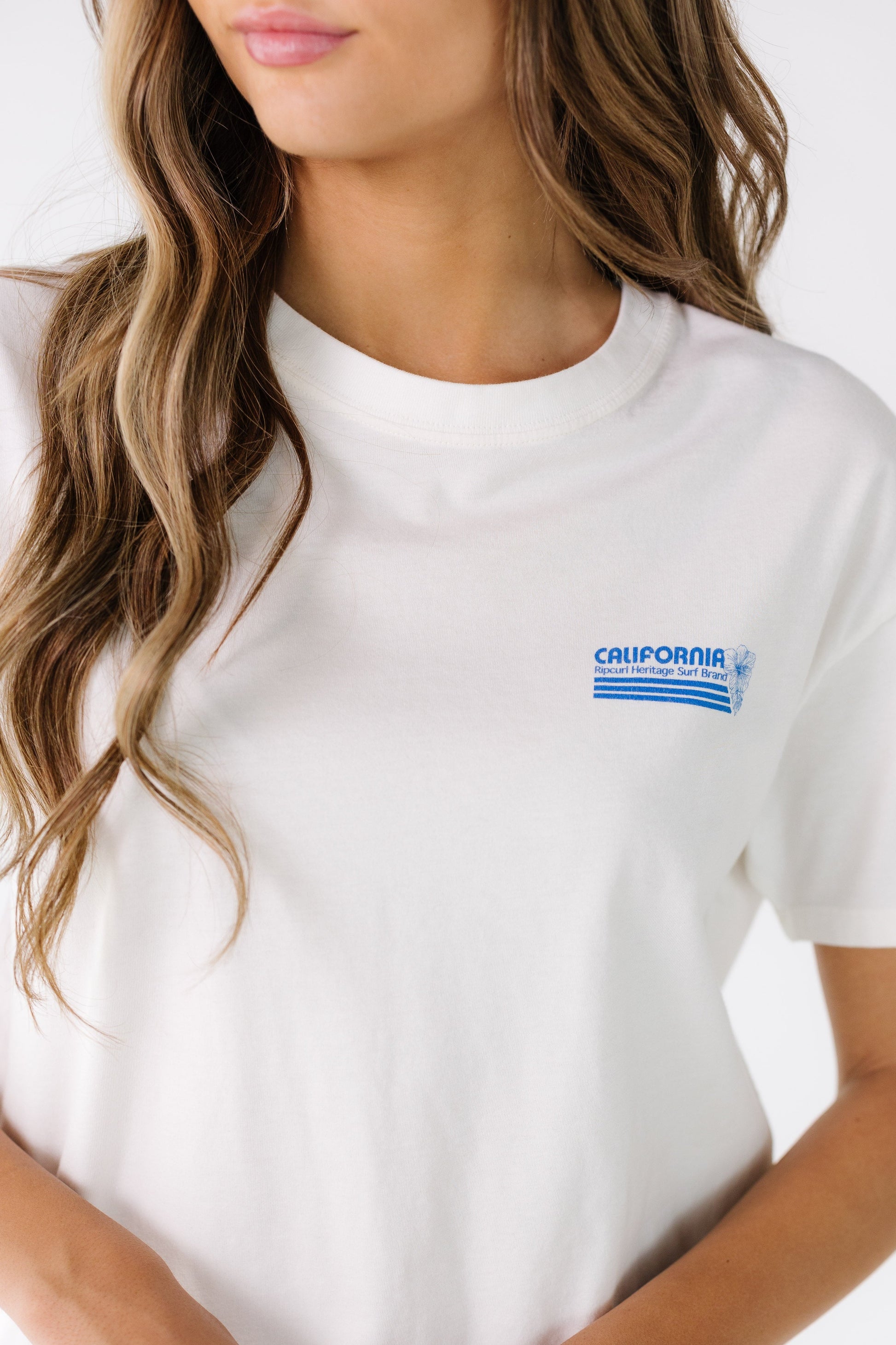 Close view of a young woman wearing a Rip Curl graphic tee with a small front graphic.