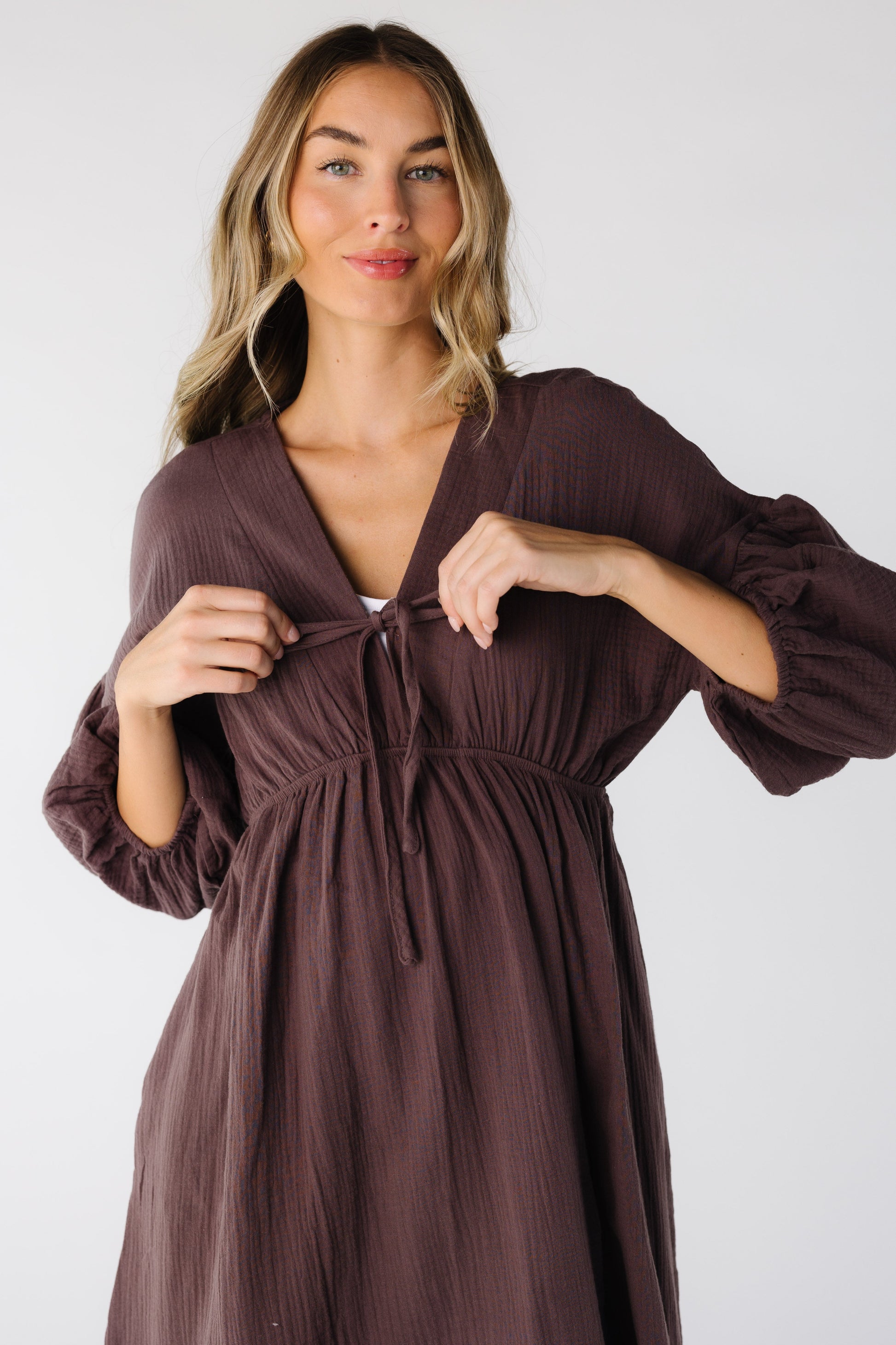 Close view of woman wearing a brown dress with V-neckline and three quarter length sleeves