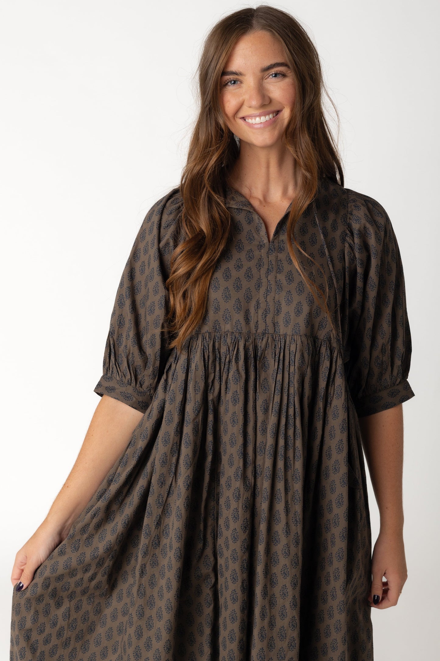 Closes view of brown and black loose midi dress with V-neckline with ties and half length sleeves