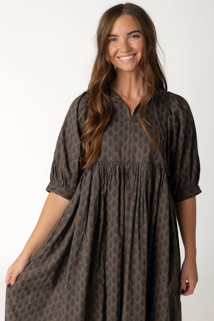 Closes view of brown and black loose midi dress with V-neckline with ties and half length sleeves