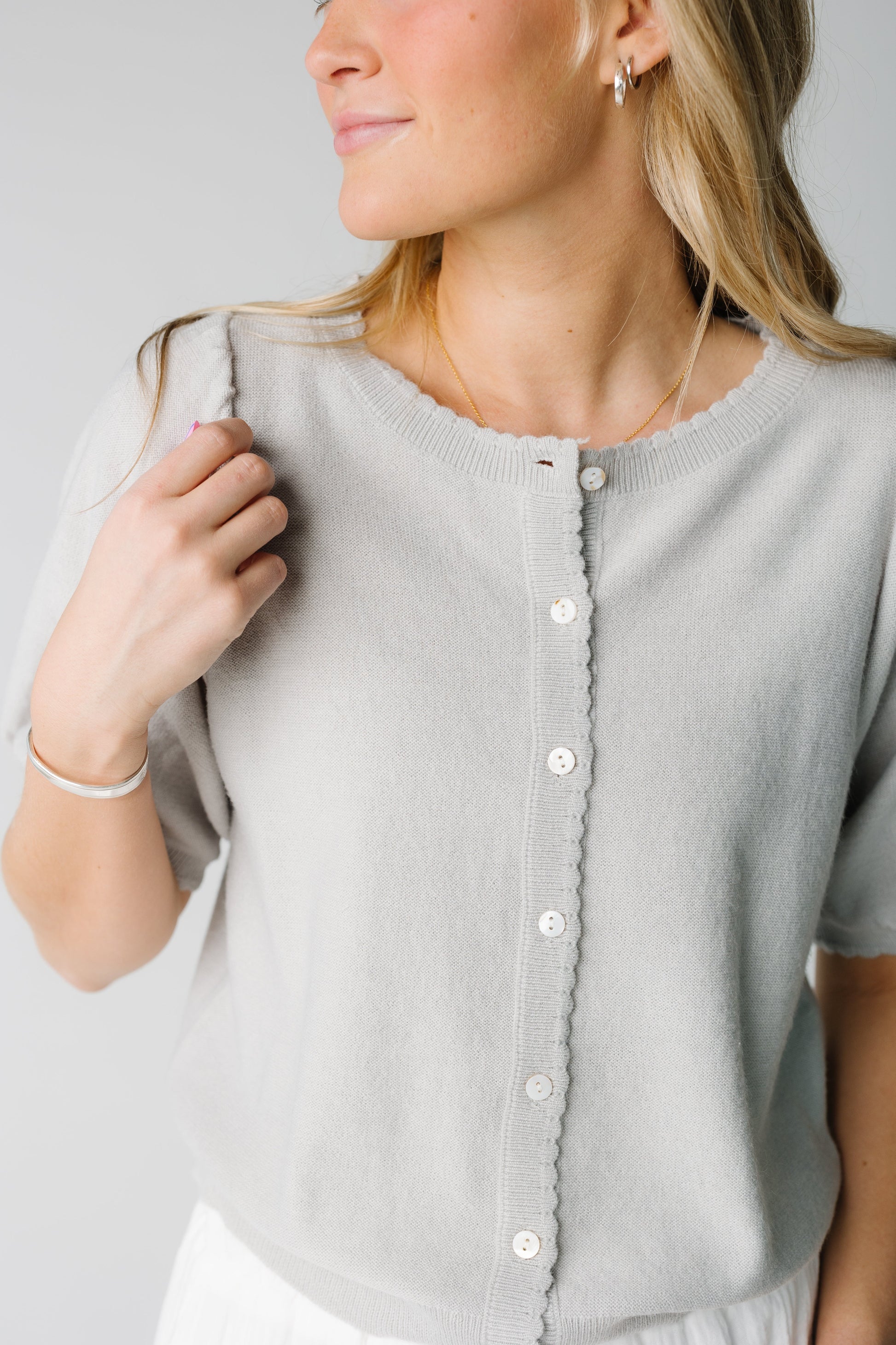 Close view of grey cardigan with scallop edges