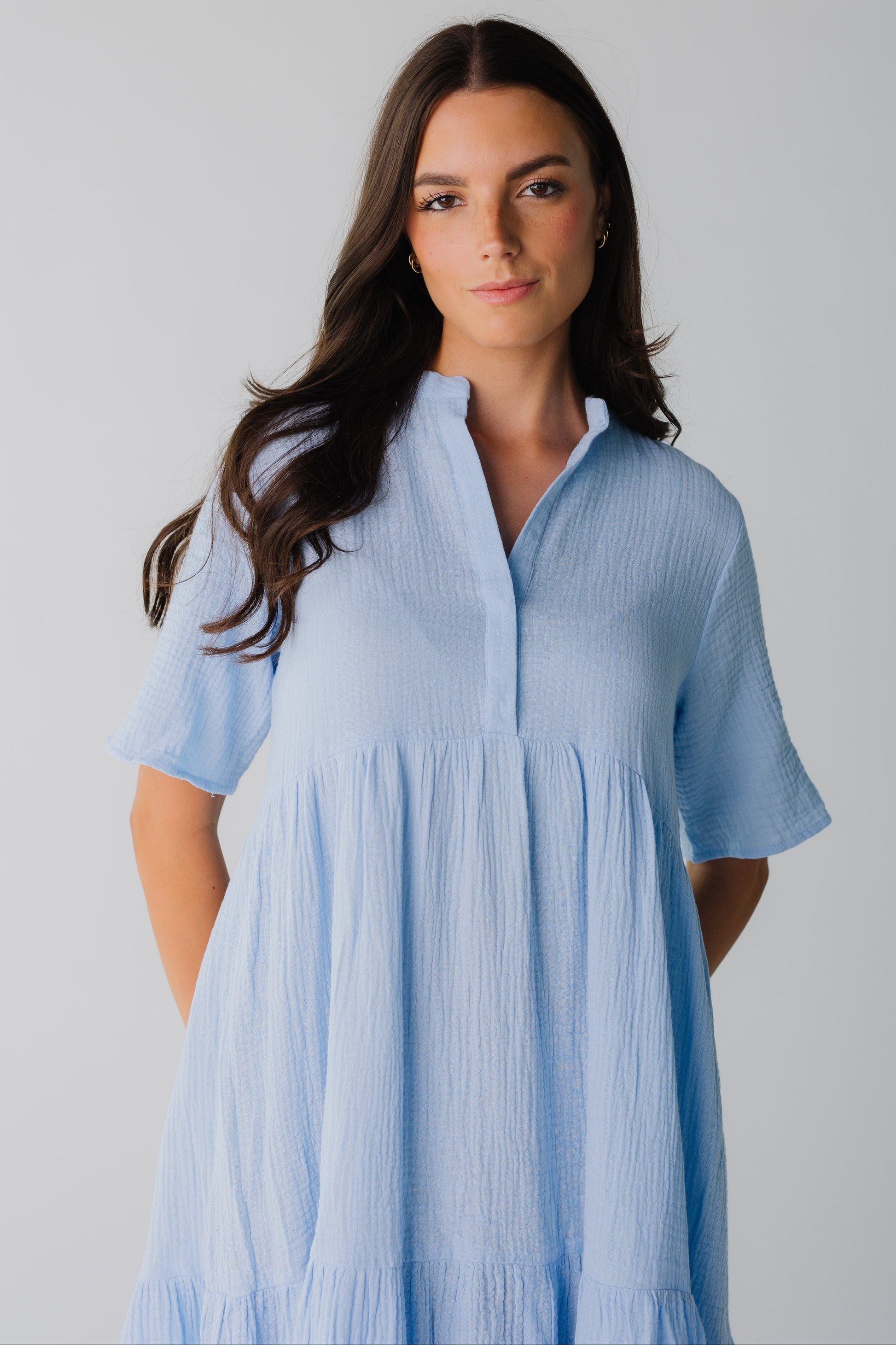 Close view of women's light blue dress with open V-neckline and short sleeves with an empire waist