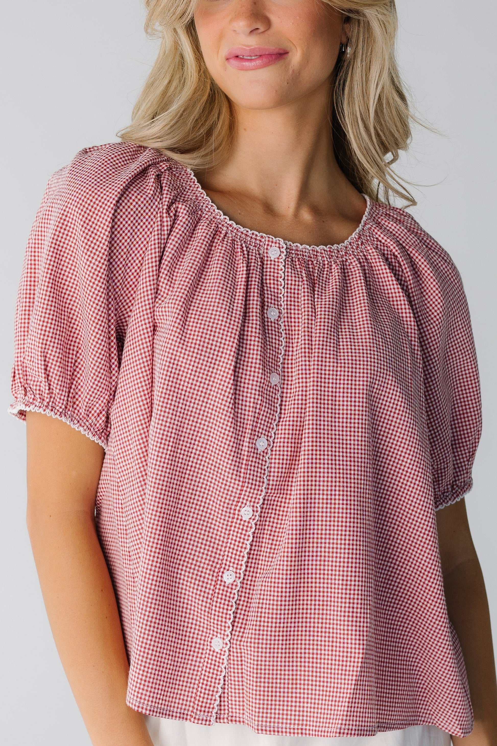 Close view of red gingham blousy button down top