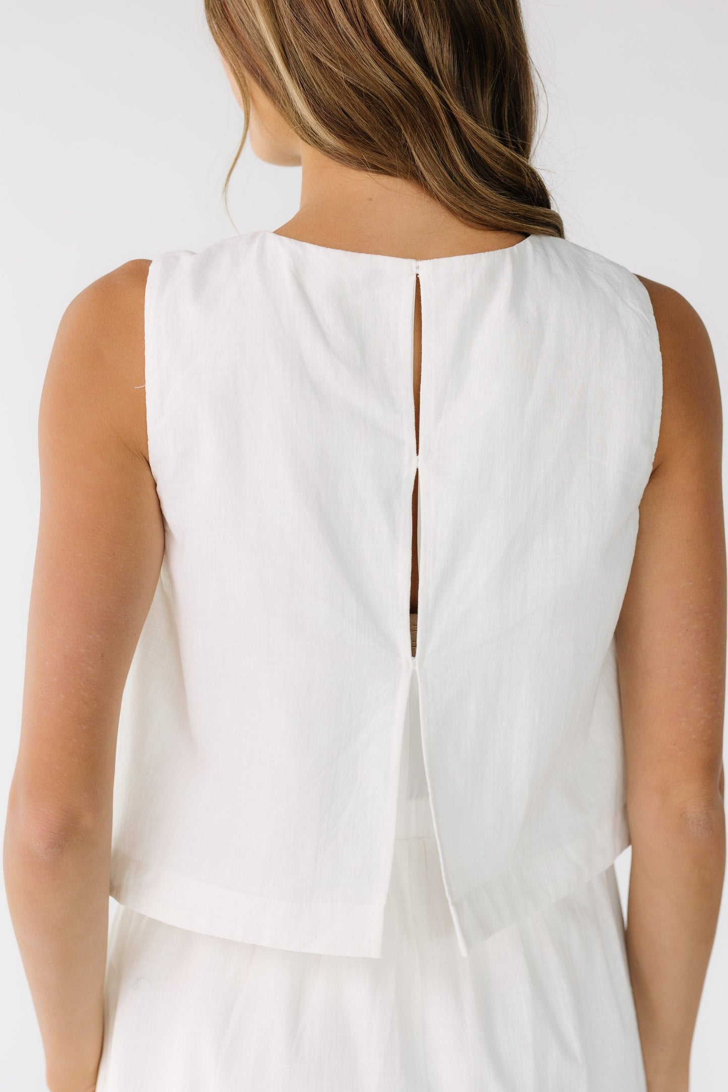 Close back view of a woman wearing a  1 piece dress with 3 hidden button closure.