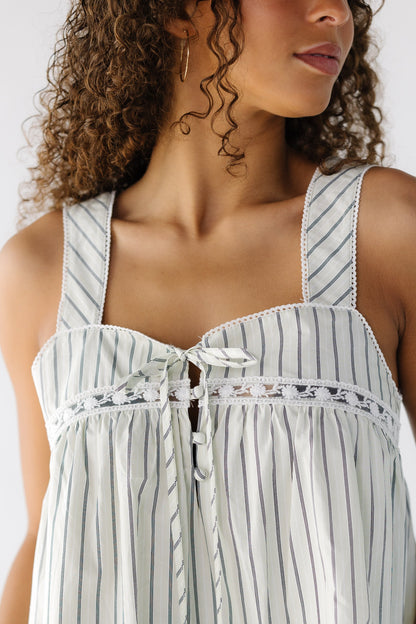 Close up the a teen girl wearing an off white and black stripe jumper dress with bodice buttons, wide shoulder straps and lace insets around the short bottom bodice.