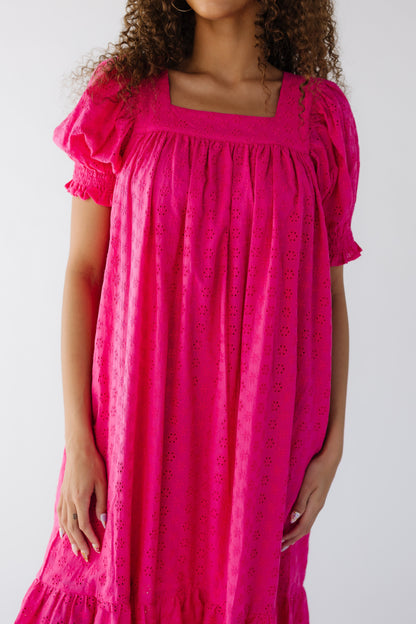 Closer view of a teen girl wearing a  deep pink eyelet midi dress with a square neckline, and puff sleeves with  smocked cuff.