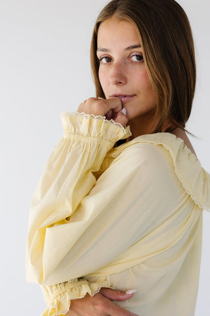 Young woman wearing a modest  light yellow long sleeve blouse with lace trimmed cuffs and collar.