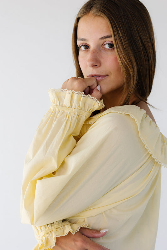 Young woman wearing a modest  light yellow long sleeve blouse with lace trimmed cuffs and collar.