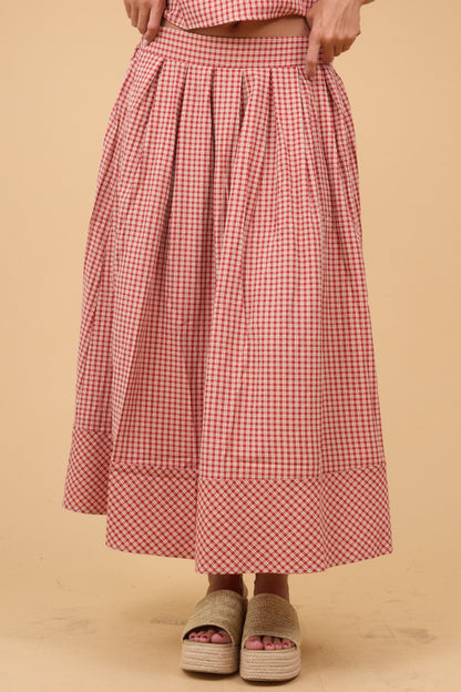 Woman wearing a red plaid midi skirt with front pleats and a wide waistband.