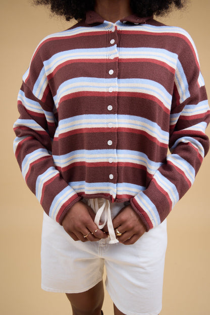Close view of a woman wearing a brown multicolor & stripe button down cardigan with long sleeves.
