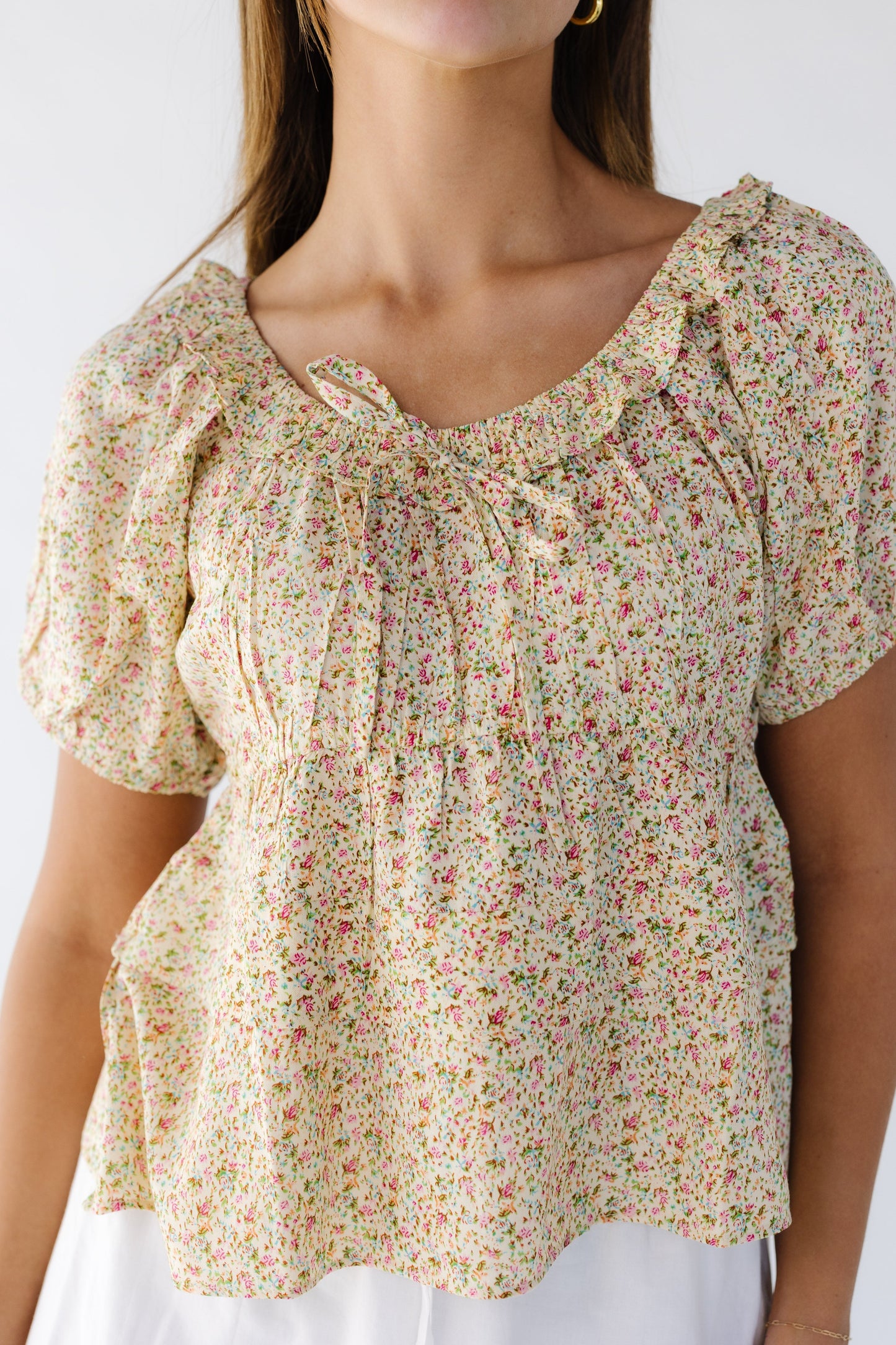 Close view of a yellow floral print empire waist blouse with double ruffle bottom, ruffled scoop neckline and short puff sleeves.