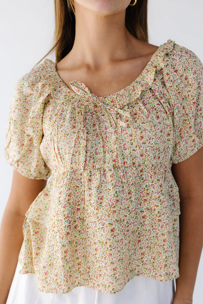 Close view of a yellow floral print empire waist blouse with double ruffle bottom, ruffled scoop neckline and short puff sleeves.