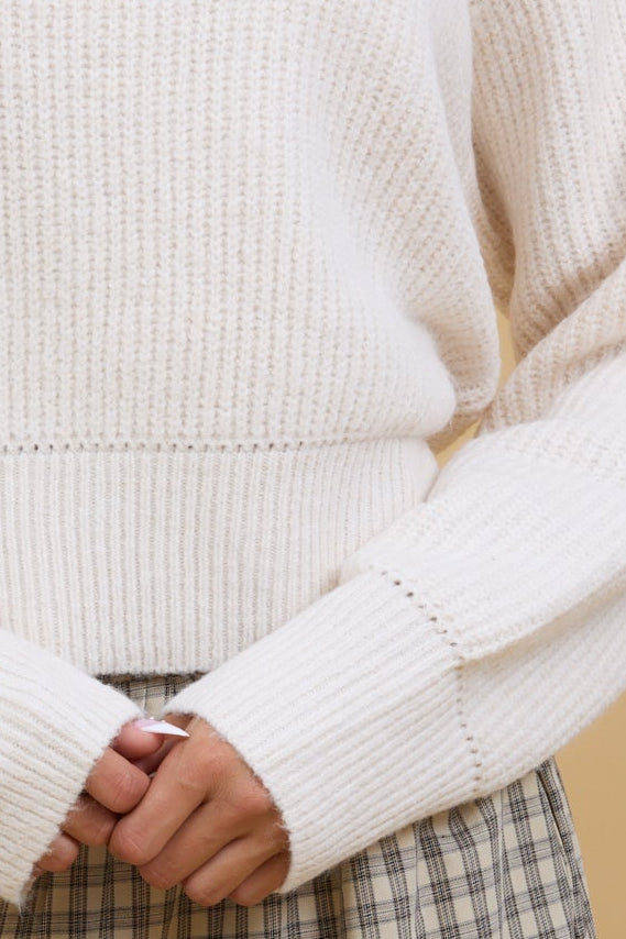Close view of a young woman showint the eyelet detail on a long sleeve, eyelet pullover sweater.