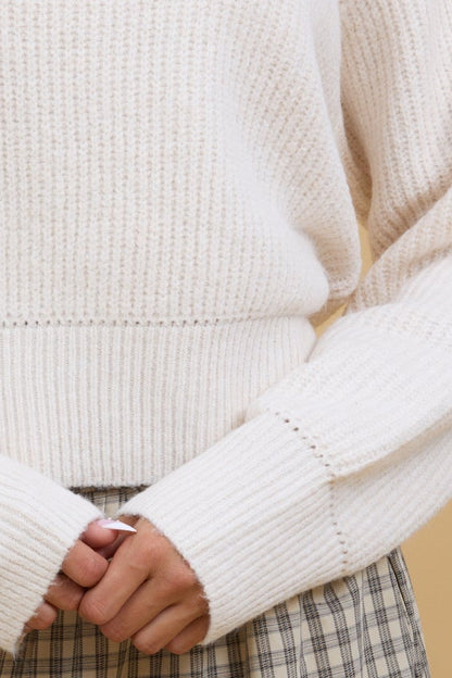 Close view of a young woman showint the eyelet detail on a long sleeve, eyelet pullover sweater.