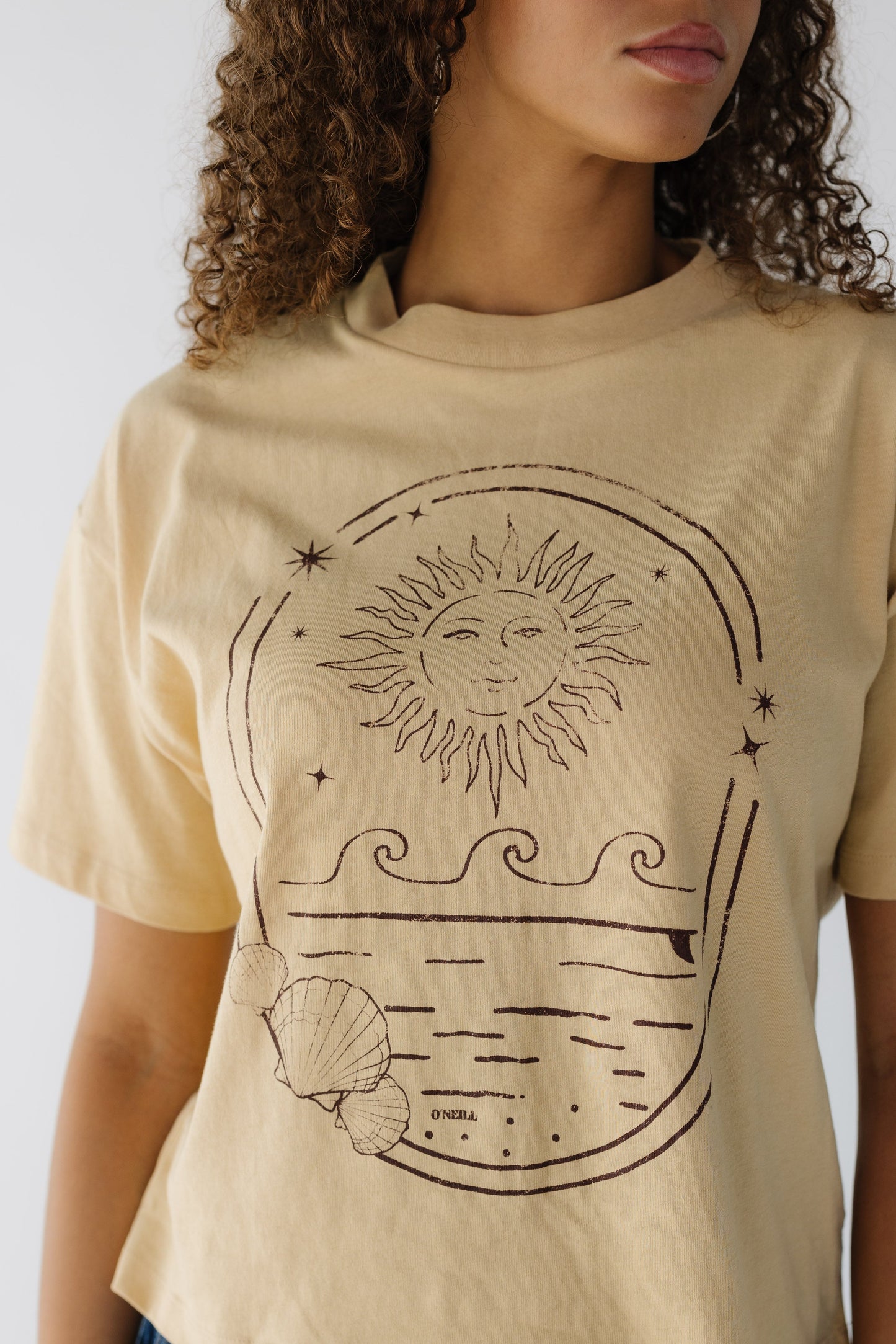 Close view of a teenage girl wearing a yellow graphic tee with short sleeve and a crew neckline.