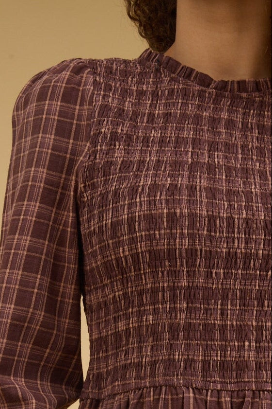 Brown plaid dress with a round, ruffle edge neckline, long sleeves and smocked bodice.