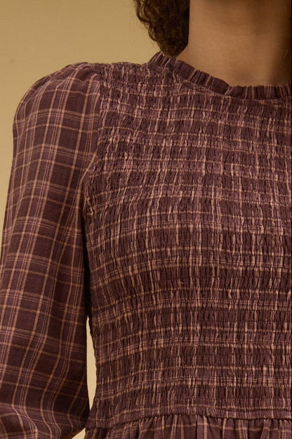 Brown plaid dress with a round, ruffle edge neckline, long sleeves and smocked bodice.