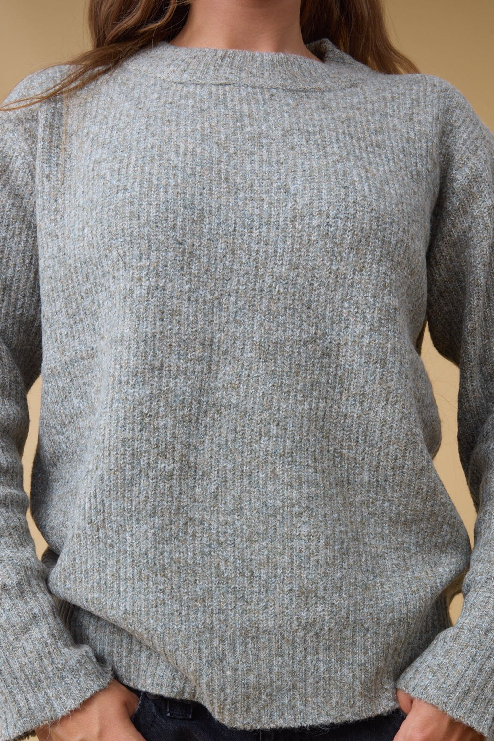 Close view of a young womn wear an all rib knit sweater with long sleeves.