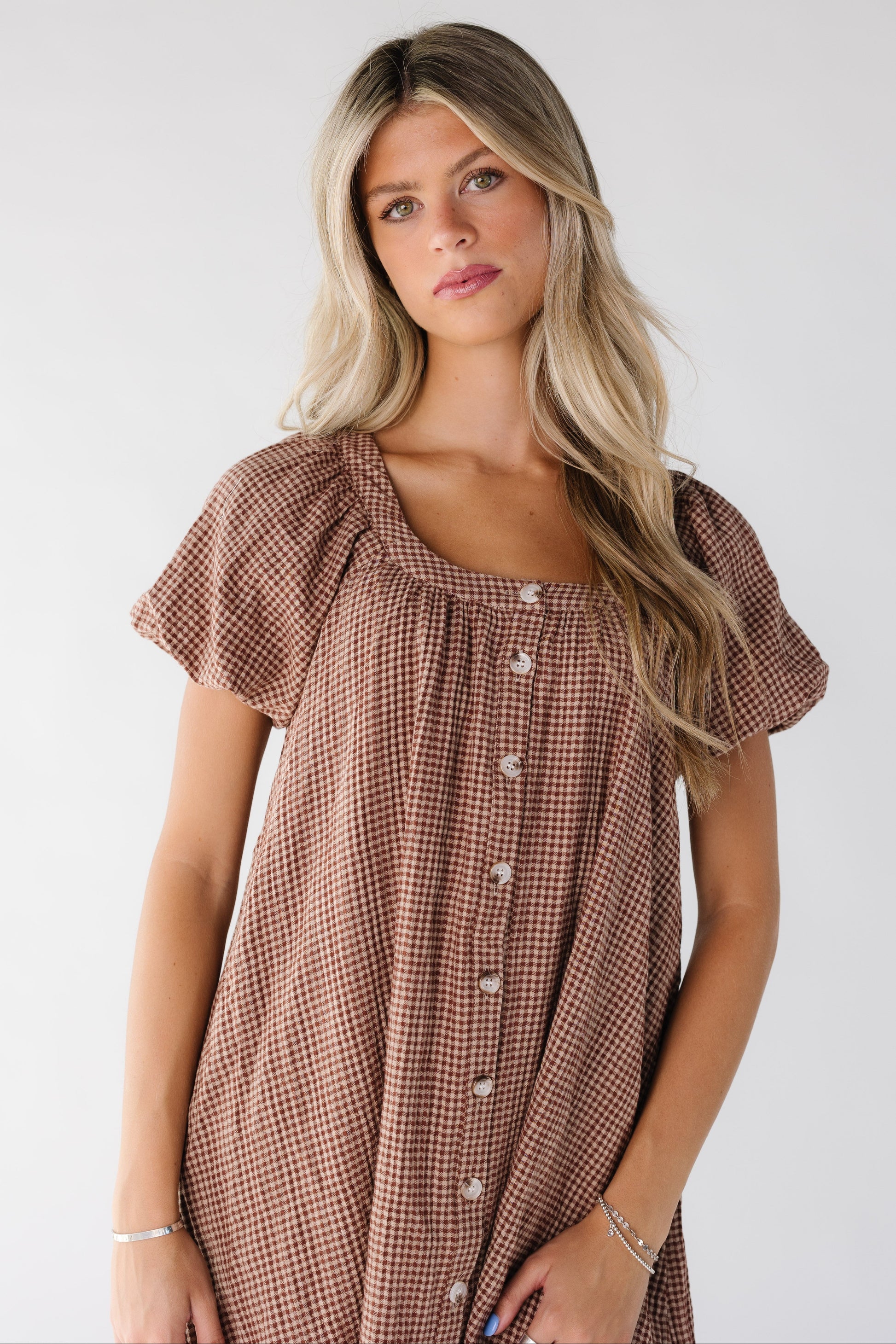 Close view of a woman wearing a brown gingham dress with a scoop neckline