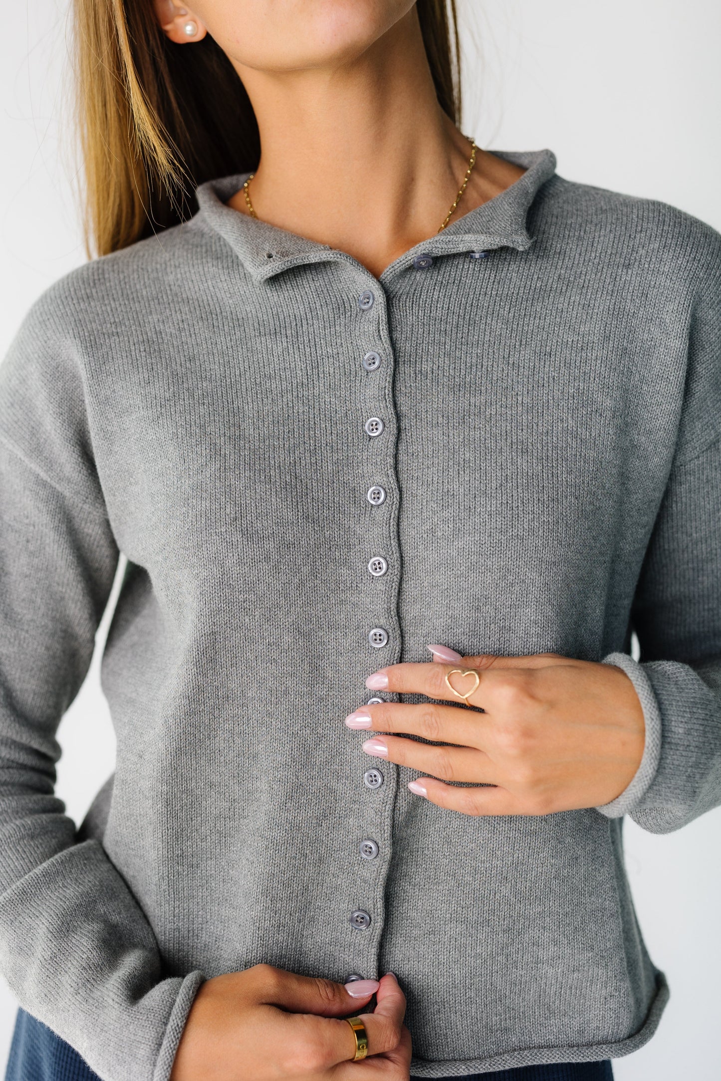Close up of a woman wearing ia grey button down cardigan with long sleeves