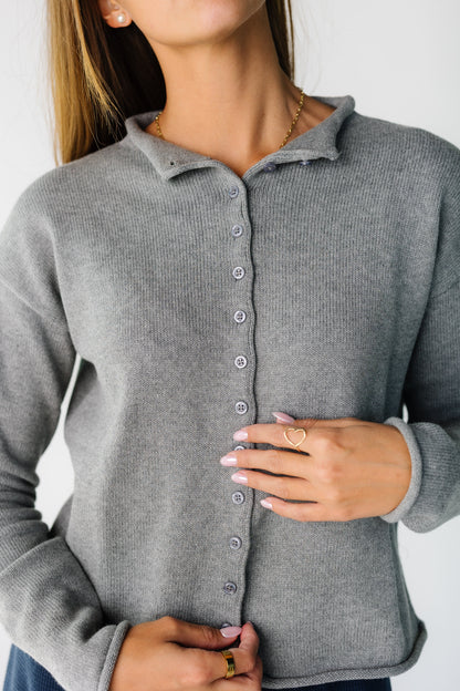 Close up of a woman wearing ia grey button down cardigan with long sleeves