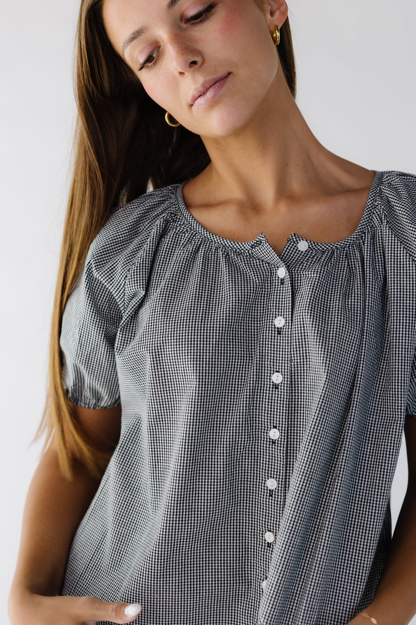 Close view of a woman wearing a black & white gingham button down top.