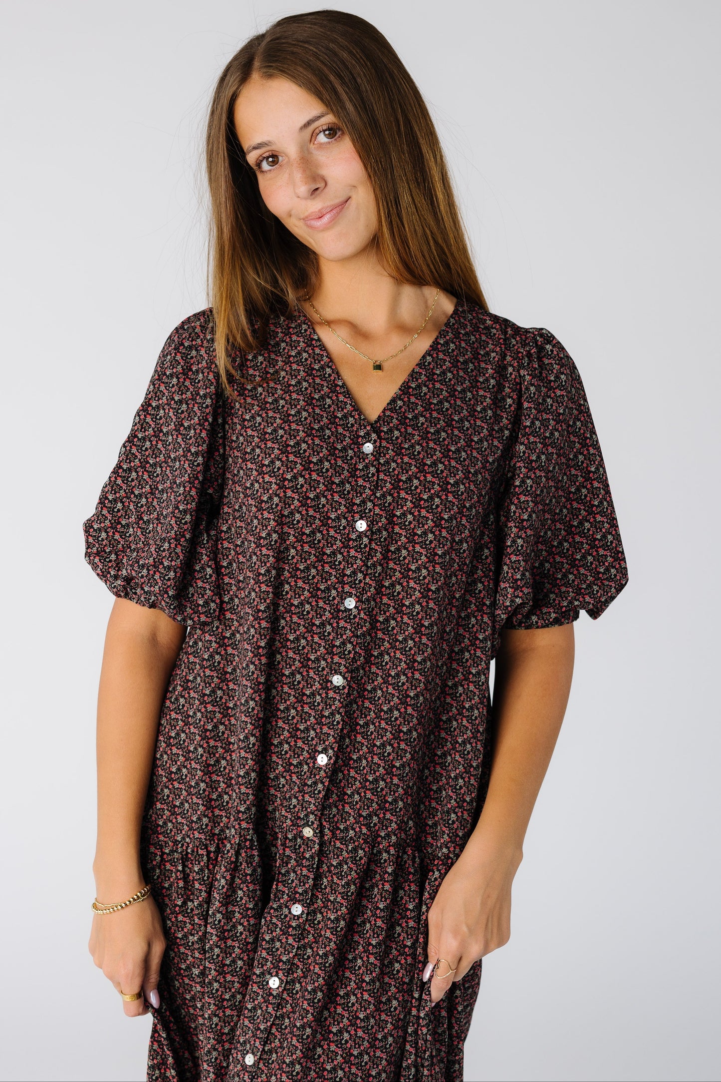 Close view of a woman wearing a loose fitting black floral button down dress with elbow length sleeves