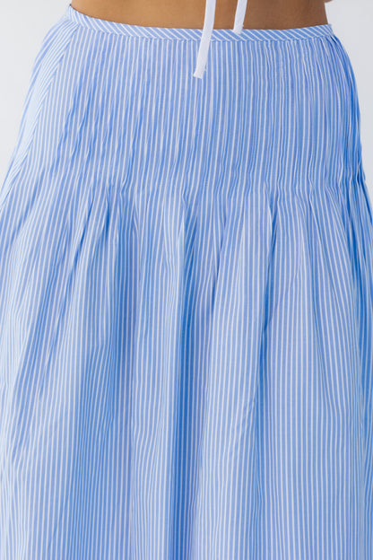 Close view of a young woman wearing a blue and white  stripe midi skirt with sewn down pleats.