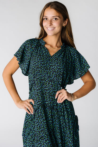 Close view of a woman wearing a blue mixed print dress with V-neckline and short flutter sleeves