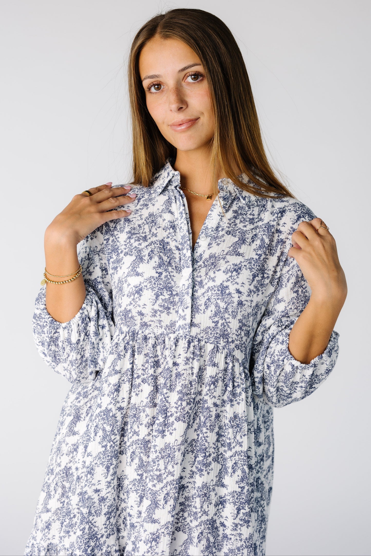 Close view of a woman wearing a white and blue floral print midi with a v-neckline