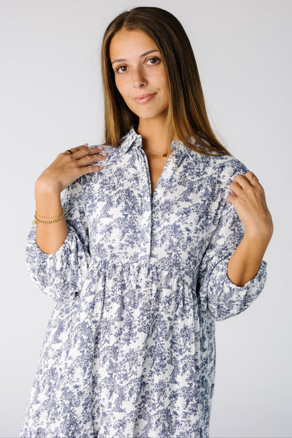 Close view of a woman wearing a white and blue floral print midi with a v-neckline