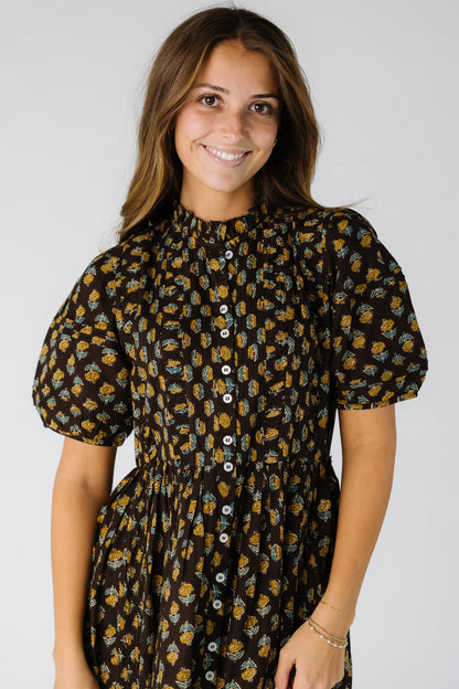 Close view of a woman wearing a brown floral button down dress with short balloon sleeves