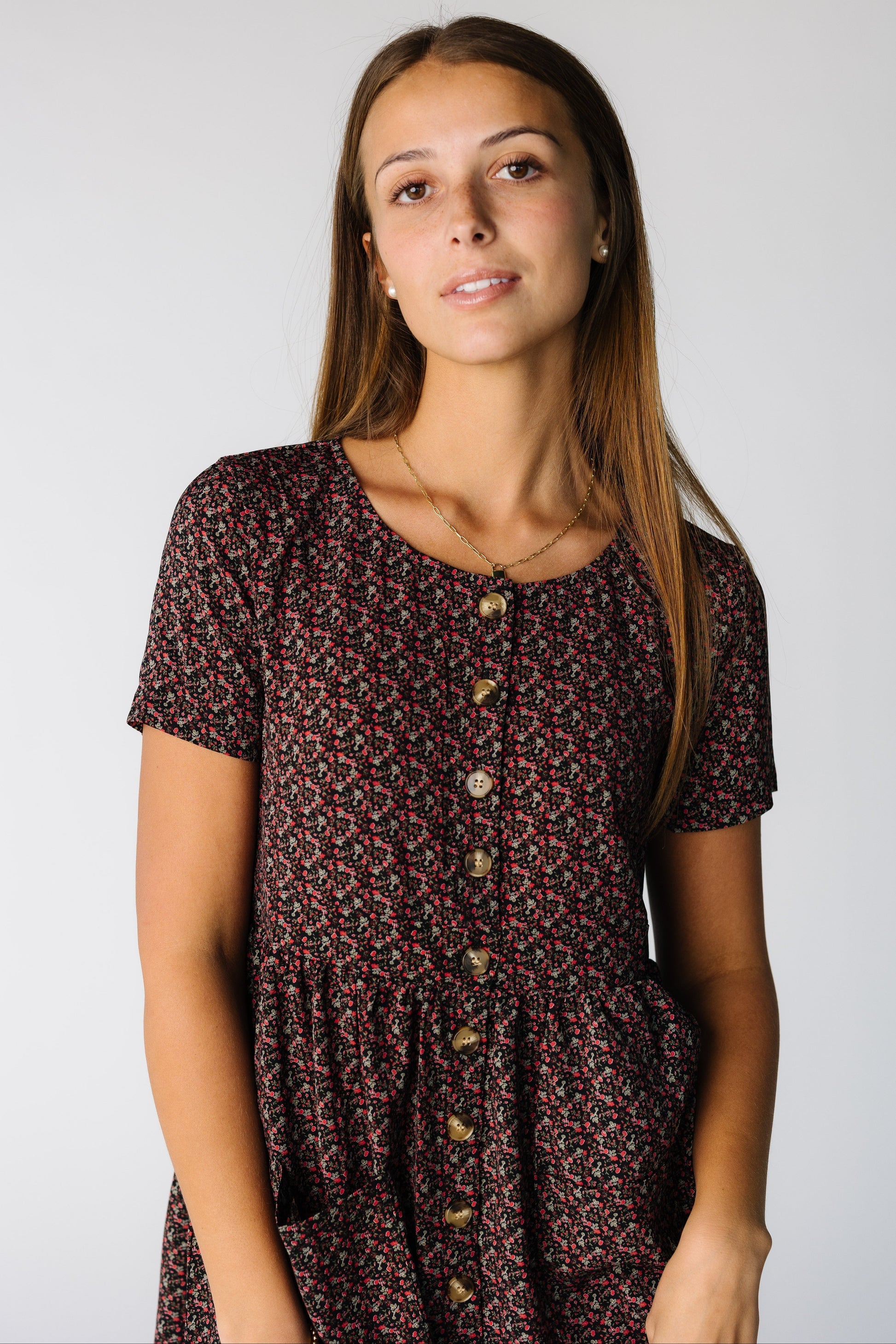 Close view of a woman wearing a black floral print dress with buttons and short sleeves