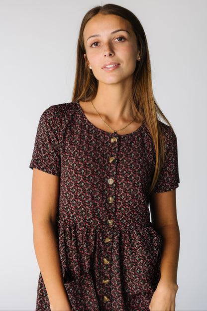 Close view of a woman wearing a black floral print dress with buttons and short sleeves