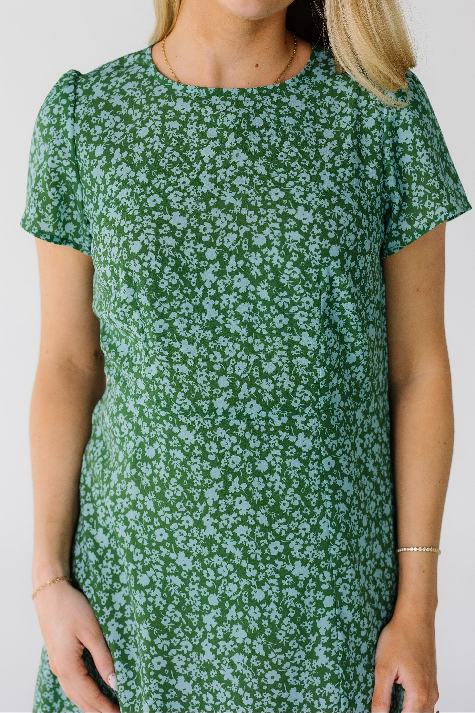 Close view of a woman wearing a green and light blue floral print dress.