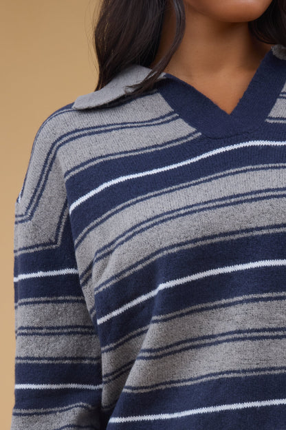 Close view of a woman wearing a stripe pullover sweater with long sleeves and a  V-neckline.