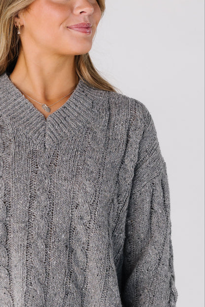 Close view of a women wearing a grey cable knit sweater