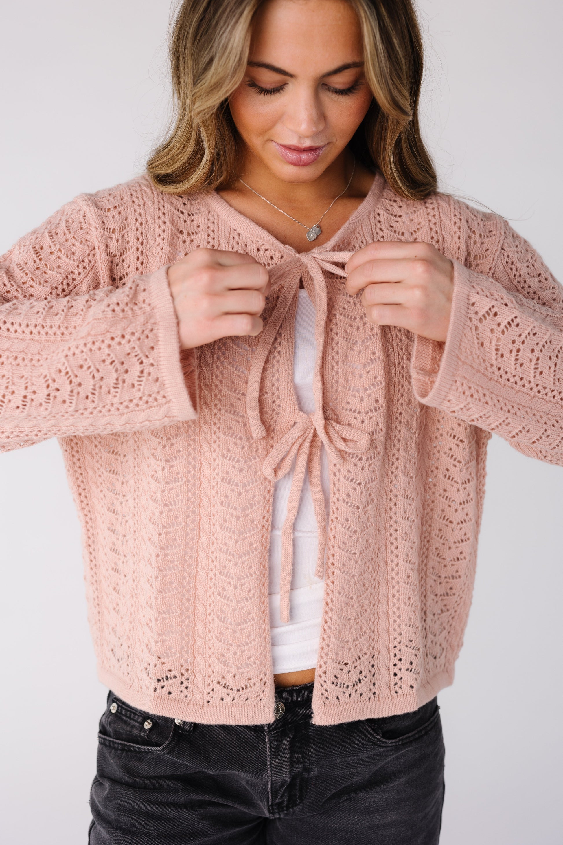 Woman wearing a pink lace cardigan with long sleeves