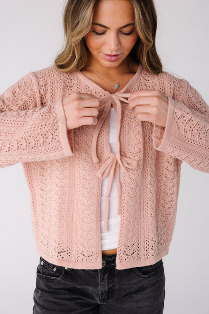 Woman wearing a pink lace cardigan with long sleeves