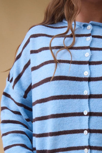 Close view of a woman wearing a light blue & brown stripe button down cardigan with long sleeves.