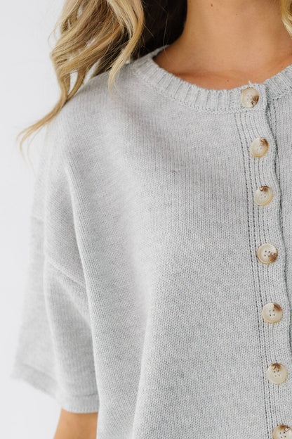 Close view of a woman wearing a grey short sleeve button down cardiagn.