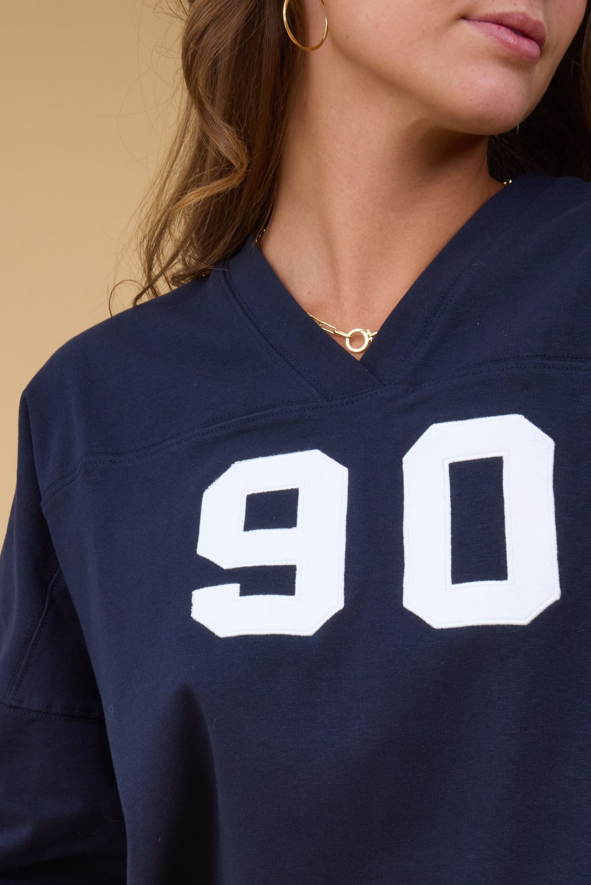 Close view of a young woman wearing a navy footbal style tee with a V-neckline and large number graphic.